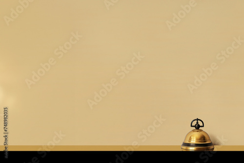 sonnette dorée et noire de la réception d'un hôtel de luxe sur le comptoir pour appeler le personnel. Fond beige avec espace négatif pour texte copyspace Hostellerie, voyages, réservation vacances  photo