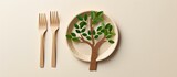 A plate featuring a tree design sits on a bright table, accompanied by a fork and knife made from environmentally friendly disposable materials like paper and wood. The plastic tree atop the plate