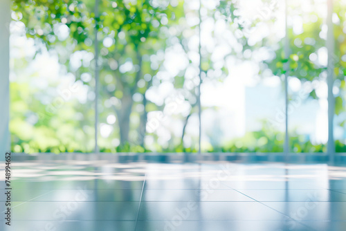 Blurred empty modern open space office with large windows and green trees on the outside, environment friendly business background