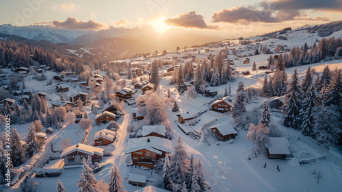 A sweeping aerial panorama of a snow-covered mountain village at dawn.
