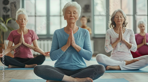 A group of elderly women are gathered in a room, engaged in various yoga poses and stretches. They are focused and determined, working on their flexibility and strength