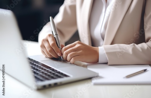 a young woman writing notes by a desk with laptop