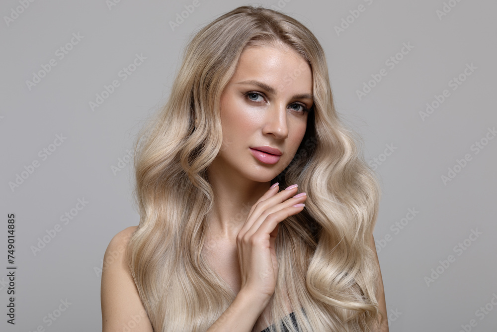 Blonde girl with long wavy hair dyeing ombre touches her hair with her hand. Beautiful fashion woman Blonde girl with long wavy hair dyeing ombre touches her hair with her hand. Beautiful fashion woman