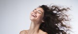 A beautiful brunette woman is seen on a white background, her hair blowing in the wind as she enjoys the feeling.