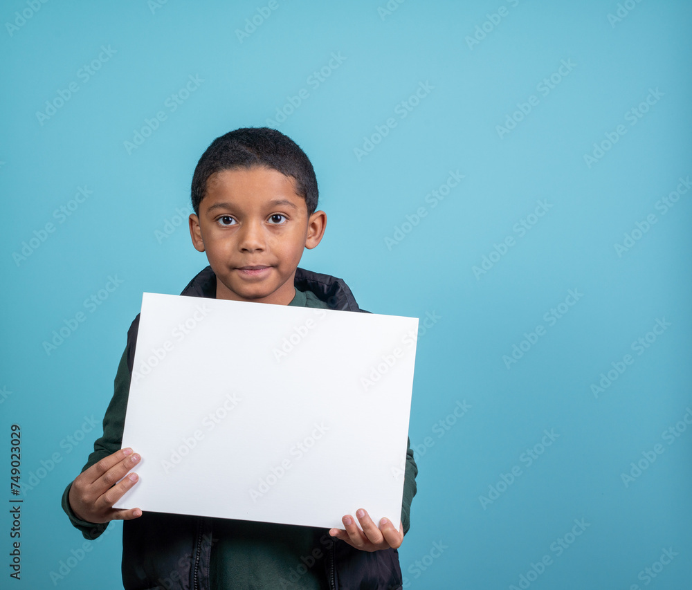 Elementery school hispanic boy looking at the camera holding a sign Elementery school hispanic boy looking at the camera holding a sign