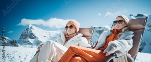 two women relaxing while sitting in a chair on snowy slopes