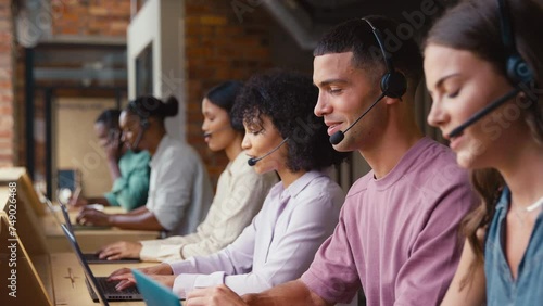 Multi-Cultural customer support or telesales team in modern open plan office wearing headsets and talking with customers - shot in slow motion