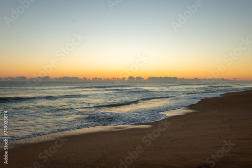 Sunrise on a Florida beach, sea foam on shore, clouds above the horizon