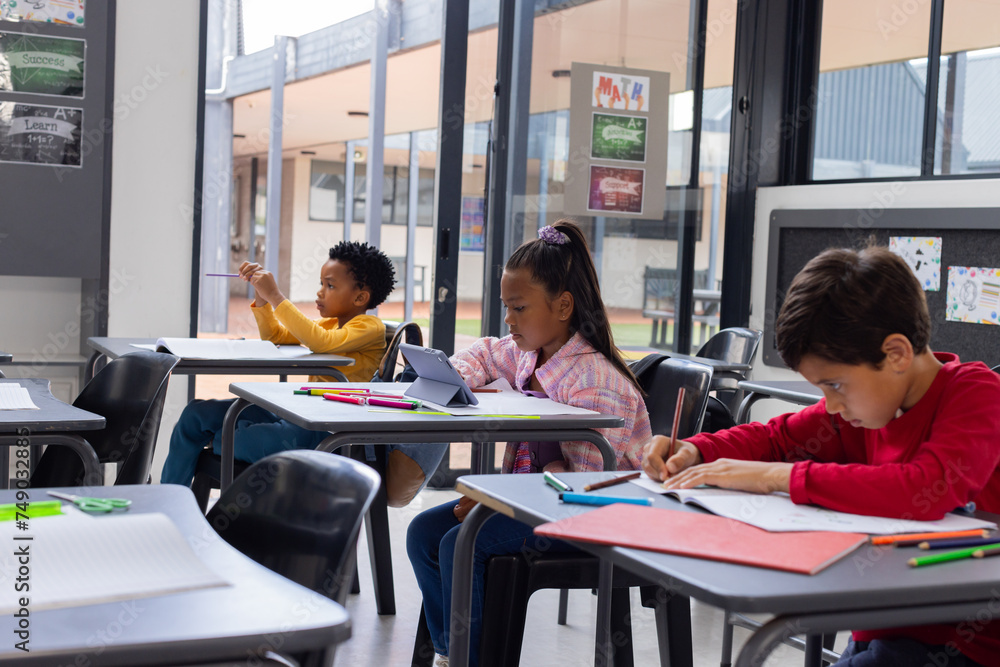 Obraz premium Biracial girl and boys are focused on their schoolwork in a school classroom