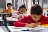 Biracial girl and boys are focused on their schoolwork in a school classroom