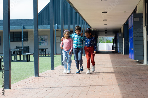 Three biracial children are walking together at school with copy space