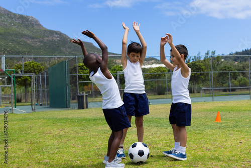 Three boys celebrate during a soccer game at school; two are biracial and one is African American