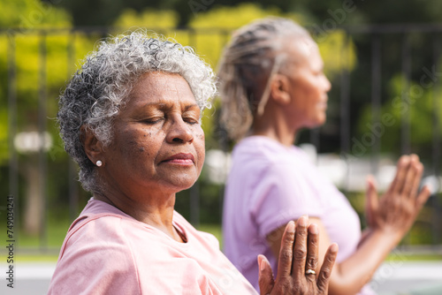 Фотография Senior African American woman and senior biracial woman practice yoga outdoors