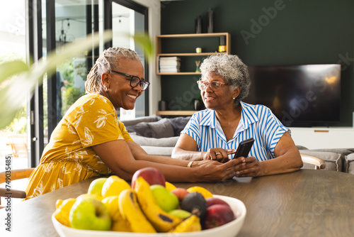 Senior African American woman and senior biracial woman share a moment at a table at home