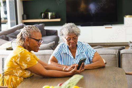 Senior African American woman and senior biracial woman are looking at a smartphone together at home