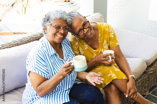Senior African American woman and senior biracial woman share a joyful moment with coffee at home