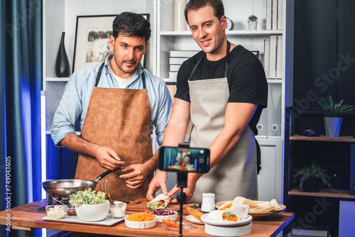 Healthy food in kitchen with chef influencers presenting fresh salad roll on cooking show streaming via smartphone on social media live, preparing ingredients vegetable soft tortilla wrap. Sellable. photo