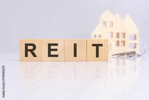 Fototapeta Naklejka Na Ścianę i Meble -  wooden cubes on a table with text REIT, model house and keys on background. concept of business, financial, investment, economy. gray background