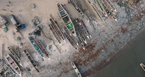 Aerial 360 zoom out.   Colourful pirogue boats lie anchored in the polluted Senegal River. Plastic pollution lines the ocean front, Saint-Louis, Senegal, Unesco World Heritage Site photo