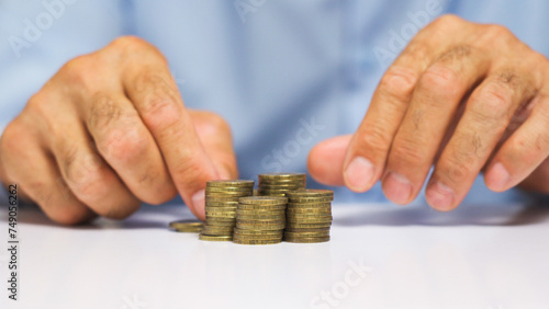 A man's hand moves stacks of coins across the table. Creative concept of stock market movement.