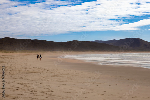 Lone couple walking on a deserted beach, Spirits Bay, New Zealand