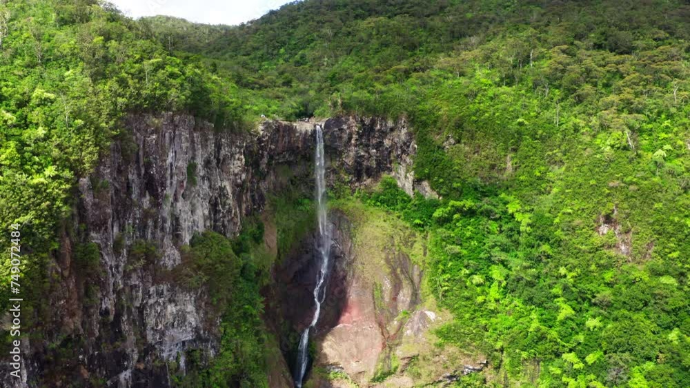 Picturesque flying over the mountain creek fall down from steep high cliff to wide green jungle valley. Cascade 500 Pieds waterfall also known as Cascade des Galets on Mauricius island in Indian ocean Picturesque flying over the mountain creek fall down from steep high cliff to wide green jungle valley. Cascade 500 Pieds waterfall also known as Cascade des Galets on Mauricius island in Indian ocean