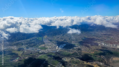 An aerial shot of southern California with vast buildings of homes and office buildings, majestic mountain ranges and blue sky with clouds in California USA