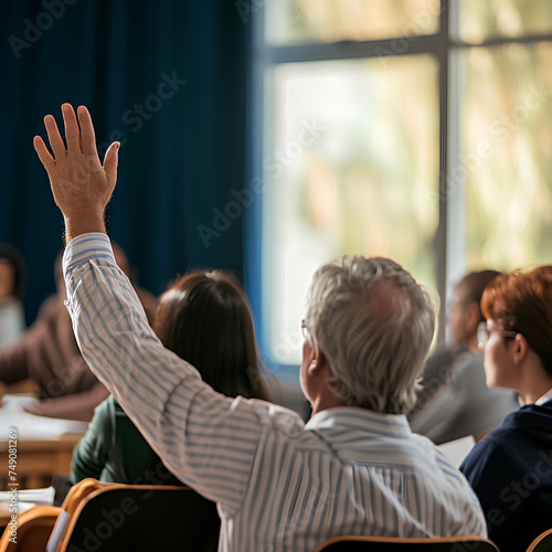 Back view of older student, Back view of older student raising his hand to answer teacher's question during education training class