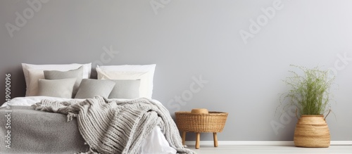 A stylish bedroom with a cozy grey stucco wall, featuring a bed adorned with a thick yarn blanket and a plant placed in the corner.