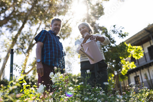 Senior biracial woman and man are tending to garden flowers photo