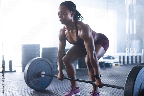 Strong biracial woman performs a deadlift in a gym setting photo