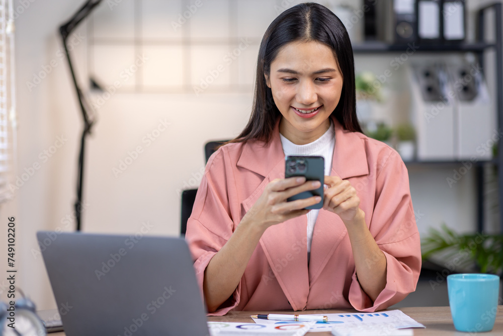 Portrait of happy young asian woman accountant working documents on laptop and phone desk using calculator for calculate finance report in home office Portrait of happy young asian woman accountant working documents on laptop and phone desk using calculator for calculate finance report in home office