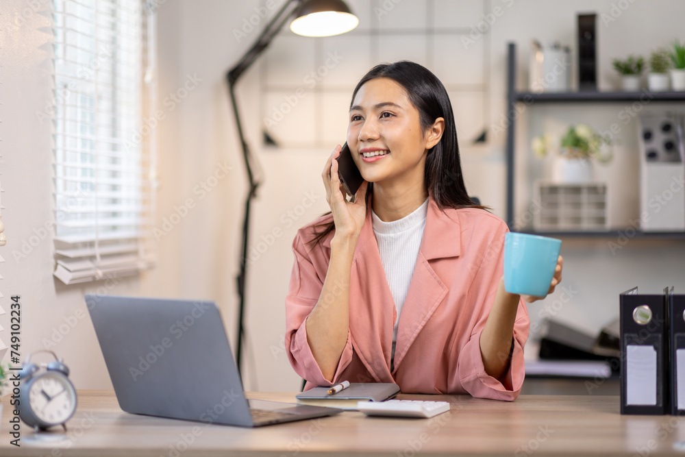 Portrait of happy young asian woman accountant working documents on laptop and phone desk using calculator for calculate finance report in home office Portrait of happy young asian woman accountant working documents on laptop and phone desk using calculator for calculate finance report in home office