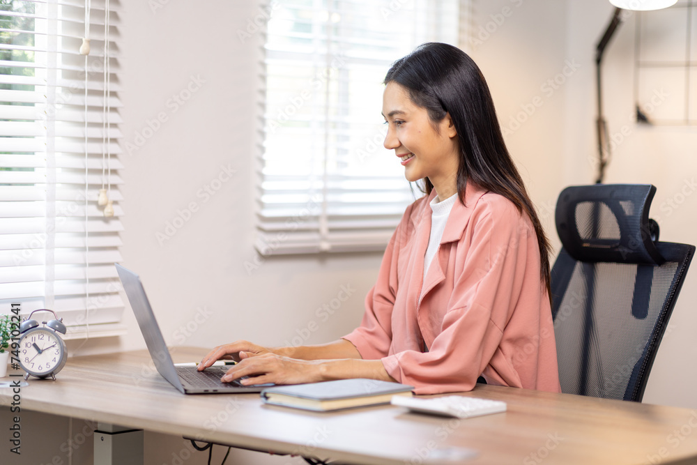 Portrait of happy young asian woman accountant working documents on laptop and phone desk using calculator for calculate finance report in home office Portrait of happy young asian woman accountant working documents on laptop and phone desk using calculator for calculate finance report in home office