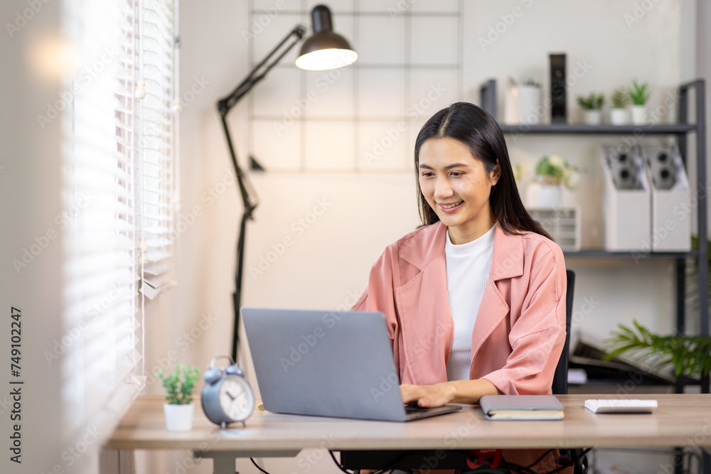 Portrait of happy young asian woman accountant working documents on laptop and phone desk using calculator for calculate finance report in home office Portrait of happy young asian woman accountant working documents on laptop and phone desk using calculator for calculate finance report in home office