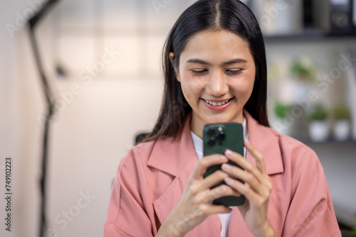 Portrait of happy young asian woman accountant working documents on laptop and phone desk using calculator for calculate finance report in home office