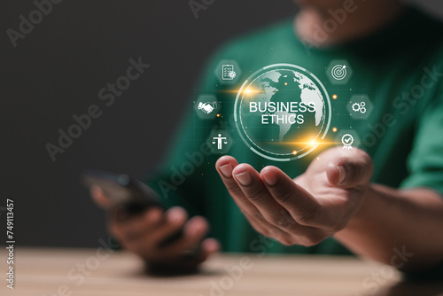 Business ethics concept. Code of ethics, moral principles, business integrity, governance policy. Person holding globe with business ethics  icon on virtual screen. photo
