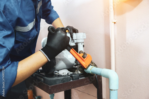 Technician plumber using a wrench to repair a water pump pipe. Concept of maintenance, fix water plumbing leaks drop or house bathroom service or cleaning clogged pipes is dirty or rusty. photo