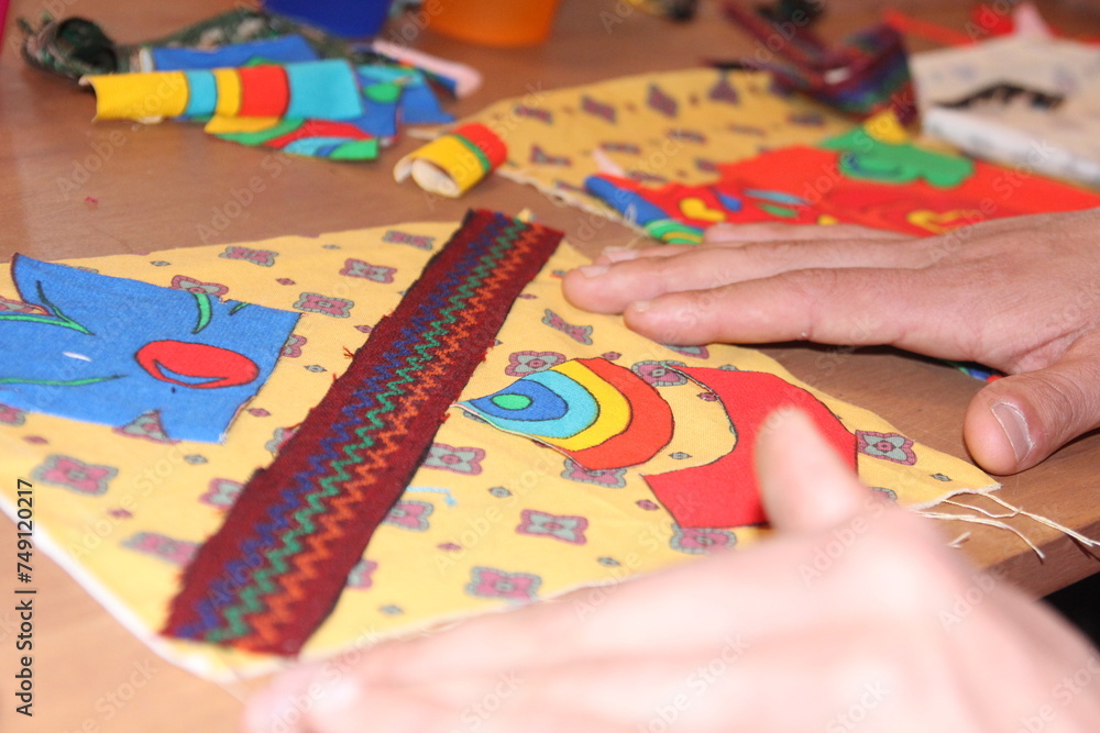 Naklejka premium A person focused on cutting, folding and pasting construction paper to create a colorful and beautiful kite.