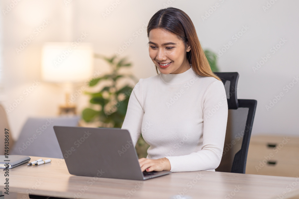 Beautiful young asian business woman working on her laptop in her home office. Beautiful young asian business woman working on her laptop in her home office.
