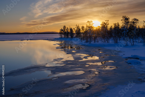 Sunrise above icy water with snow in the Pallas-Yllästunturi National Park, above the arctic circle in the north of Finland.