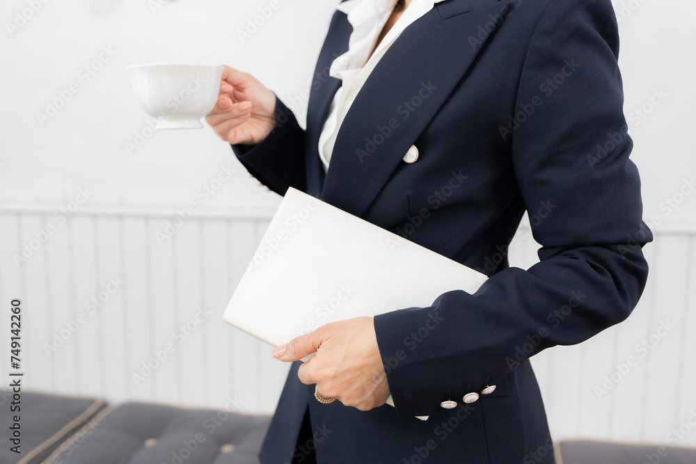 Headshot of an Asian businesswoman reading a book about investing and stocks, drinking coffee in a cafe, wearing a suit, in an office space that is a cafe. Clean, white space Headshot of an Asian businesswoman reading a book about investing and stocks, drinking coffee in a cafe, wearing a suit, in an office space that is a cafe. Clean, white space