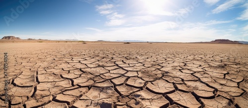 A barren desert landscape with cracked dry arid ground stretches into the distance under a clear blue sky, symbolizing the impact of severe drought and global warming on World Water Day in March.