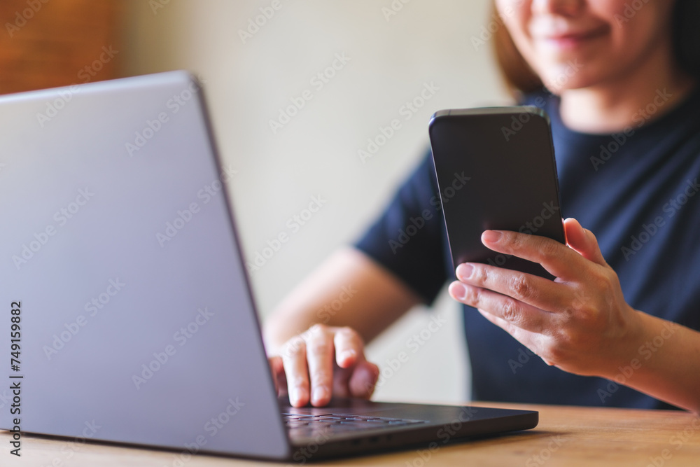 Closeup image of a young woman using smart phone and laptop computer Closeup image of a young woman using smart phone and laptop computer