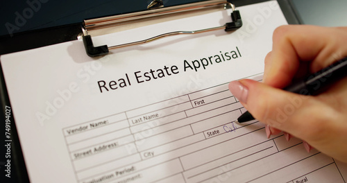 Close-up Of A Woman's Hand Filling Real Estate Appraisal Form