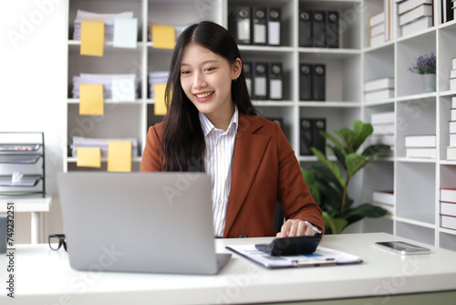 Happy Asian businesswoman working analyzing financial documents, invoices, calculating accounting and financial planning.