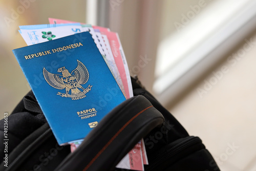 Blue Republic Indonesia passport with money and airline tickets on touristic backpack close up. Tourism and travel concept photo