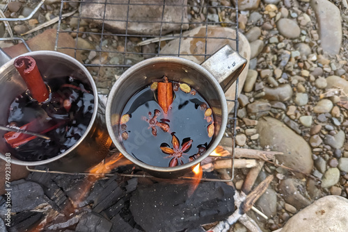 Mulled wine in metal mugs with spices on a stone beach. photo