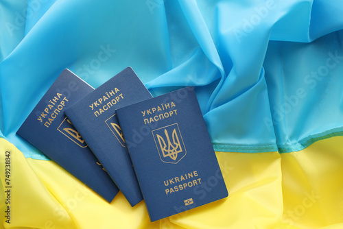 Three Ukrainian biometrical passports on folded waving flag of Ukraine country close up photo