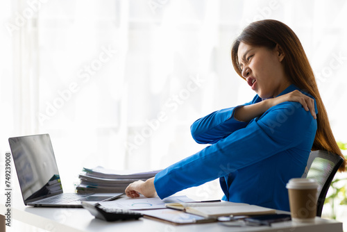 Woman who are serious about working in the office are having aches and pains in their shoulders and waist, office syndrome. photo